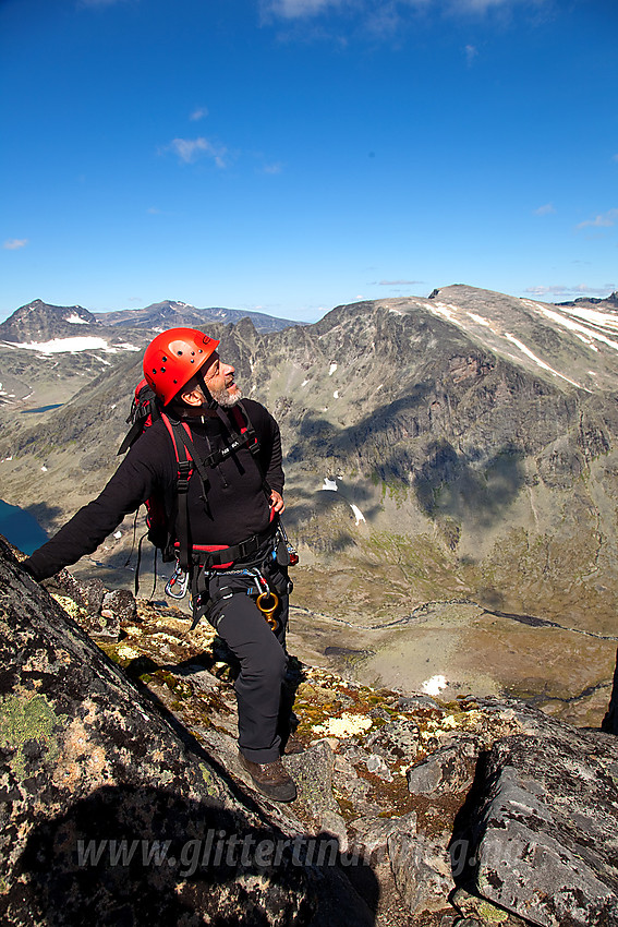 Gunnar står og betrakter personer som rappellerer ned første hammer vest for Midtre Torfinnstinden. I bakgrunnen bl.a. Kalvehøgde.