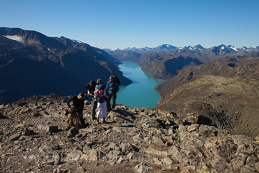 Fjellvandrere på toppen av Besseggen med Gjende i bakgrunnen.