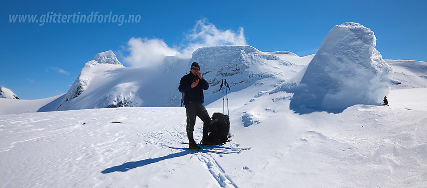 Ved den flotte varden på toppen av Brattebakken med Lodalskåpa og Veslekåpa (i en tåkesky) i bakgrunnen.