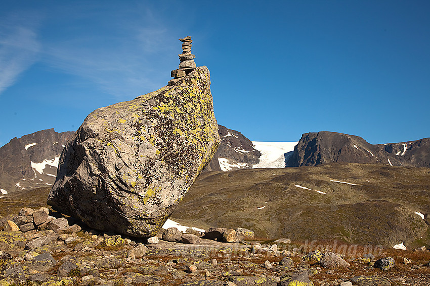 Dekorativ stein langs stien mellom Memurubu og Gjendesheim over Besseggen. I bakgrunnen ses litt av Surtningssubrean og Surtningssumassivet.