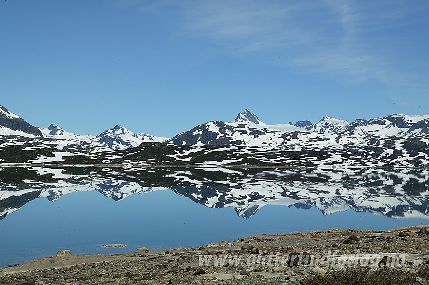 Ved Tyins østbredd med Jotunheimens tinder som speiler seg i vannet. Sentralt i bildet ses Uranostinden (2157 moh).