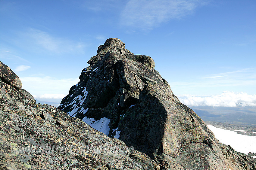 Steinflytinden (2318 moh) sett fra vest. Ryggen opp til toppen herfra, dominert av svaberglignende fjell, er både luftig og litt eksponert. Den kan være utfordrende nok i tørt vær. Enklere er toppen fra øst, eller fra vest ved å omgå litt ned og bort i sørflanken.