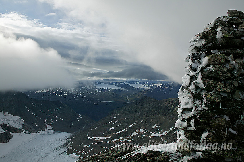 På Austre Leirungstinden (2280 moh) ved den storvokste varden en hustrig sommerkveld. På bildet ser vi nordover, bl.a. ned i Knutsholet og videre i retning Memurubreane med omkringliggende tinder.