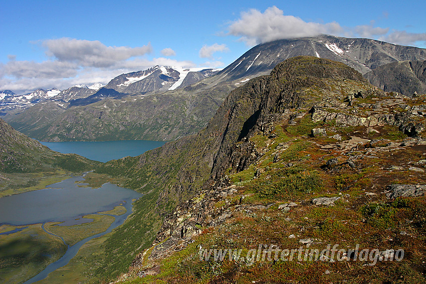 På vei over Knutshøe en flott sommerdag med toppen til høyre i bildet. Nedenunder ses Øvre Leirungen, mens Gjende ligger bakenfor. I bakgrunnen ruver Surtningssue i midten og Besshøe til høyre.