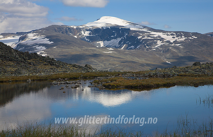 Ikke langt fra ruta mellom Juvasshytta og Raubergstulen ved noen småvann. Glittertinden speiler seg i vannet. Glitterholet og den vestre Glittertindoksla ses spesielt godt.