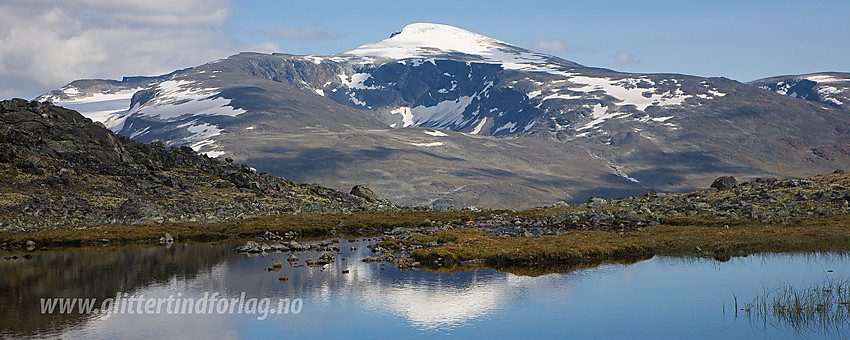 Ikke langt fra ruta mellom Juvasshytta og Raubergstulen ved noen småvann. Glittertinden speiler seg i vannet. Glitterholet og den vestre Glittertindoksla ses spesielt godt.