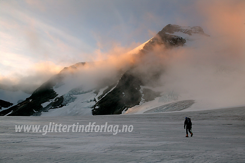 Brevandring på Gjertvassbreen. I bakgrunnen bades Gjertvasstinden (2351 moh), for anledningen omgitt av tåkeskyer, i morgensola.