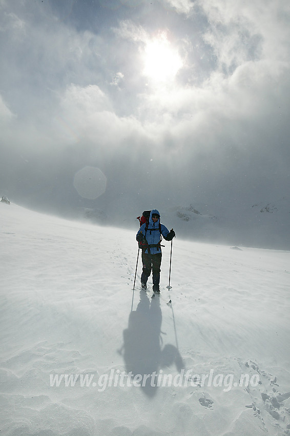 På vinterruta mellom Gjendebu og Torfinnsbu, på flatene over Veslådalen. Sola gløtter av og til gjennom skylaget og vinden får et ullent lag med snø til å fyke over flyene.