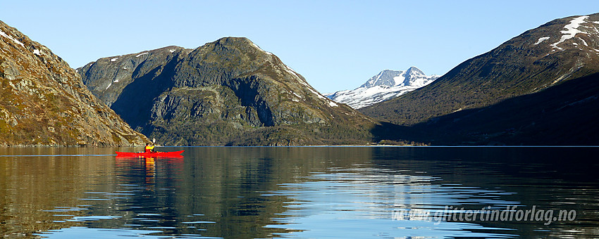 Padling på Gjende en sommermorgen. Sentralt i bakgrunnen ses Sjugurdtinden ytterst på Memurutunga. Lenger i bakgrunnen snødekte Semeltinden (2236 moh).