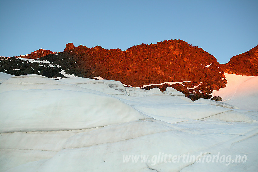 På den bratte hengebreen nordøst for Store Knutsholstinden med nordryggen på denne glødende i morgensola i bakgrunnen. Helt til venstre, langt der oppe ser man også toppen.