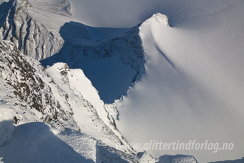 Fra ryggen like øst for Skardstinden ser vi ned på Søre Heimre Illåbreatinden (2175 moh). På bildet ses også ryggen som fortsetter nordover mot Nørdre Heimre Illåbreatinden (2170 moh). Til høyre i bildet ses en del av flata på Storjuvbrean, skjønt det er på ingen måte flatt der nede selv om det kan virke slik på bildet.